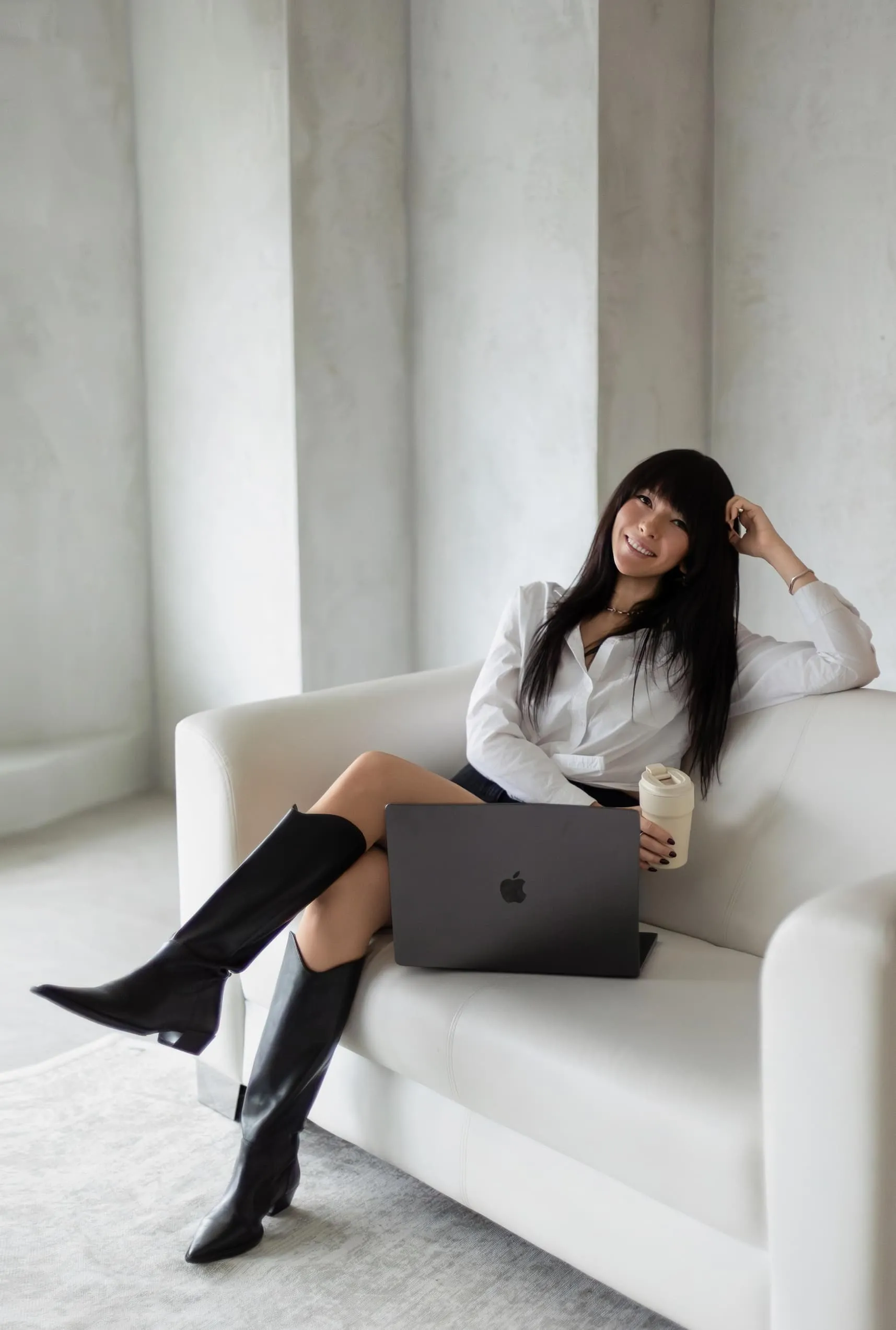 Elina on a white sofa with a laptop